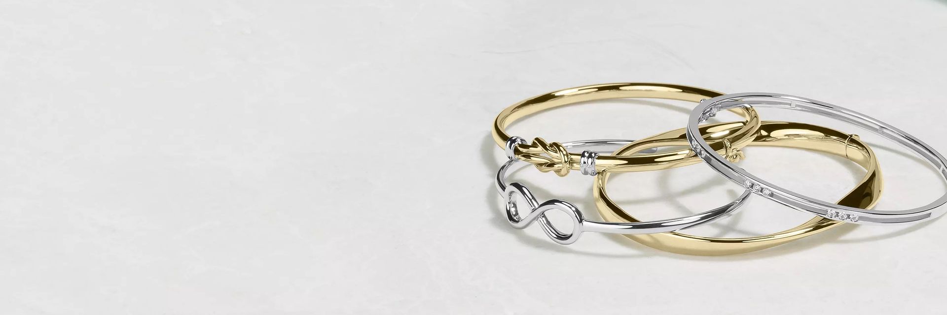 Stack of four bangle bracelets in yellow gold and white gold.