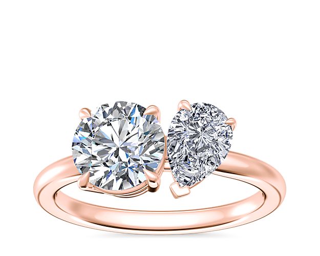 Capture the heart with this stunning engagment ring featuring a two-stone design, with a pear-cut diamond and a chosen round, princess, asscher, emerald-cut, radiant, marquise, or oval diamond for a unique look. The warm gleam of the 14k rose gold gives it a vintage-inspired look.