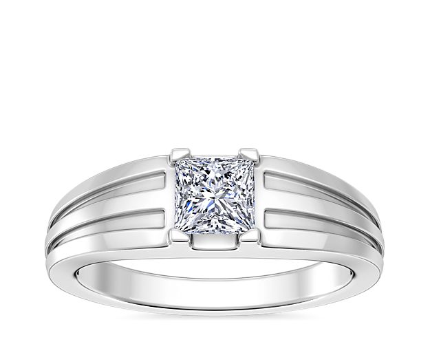 Love shines brilliantly from this engagement ring featuring an elegant center setting that  supports princess (prince), emerald-cut, and radiant-cut diamonds. The lustrous 18k white gold design features beautifully tapered and grooved stylings along the band.