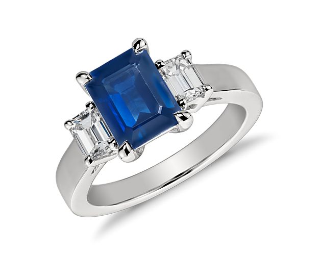 Elegantly refined, this gemstone and diamond ring showcases an emerald cut sapphire complemented by two matching emerald cut diamonds and set in enduring platinum.