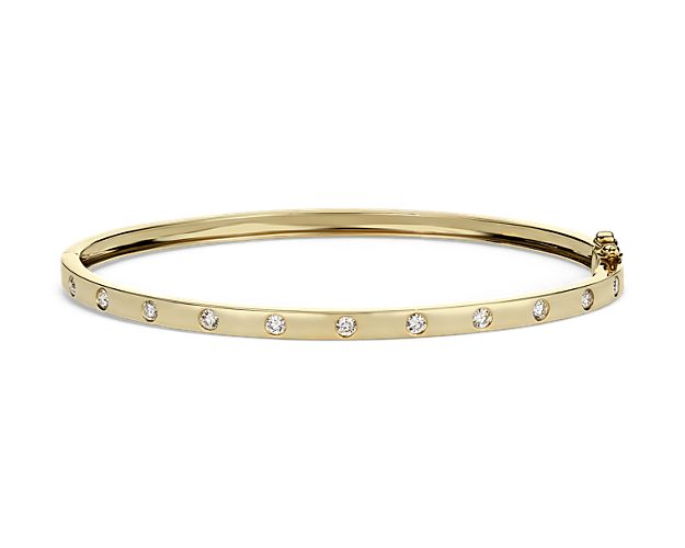 This classic bangle bracelet showcases round diamonds flush set in 14k yellow gold.