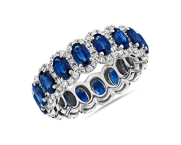 Brilliant blue sapphires nestle into individual diamond halos in this effervescent eternity ring and 14k white gold allows for maximum shine of the deeply hued stones.