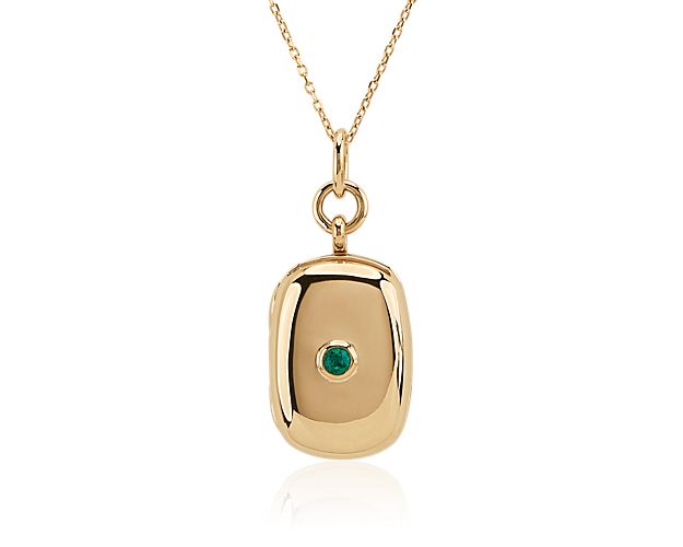 This timeless rectangular locket features a shimmering green emerald set into its center. The locket and accompanying chain are beautifully crafted from 18k yellow gold.